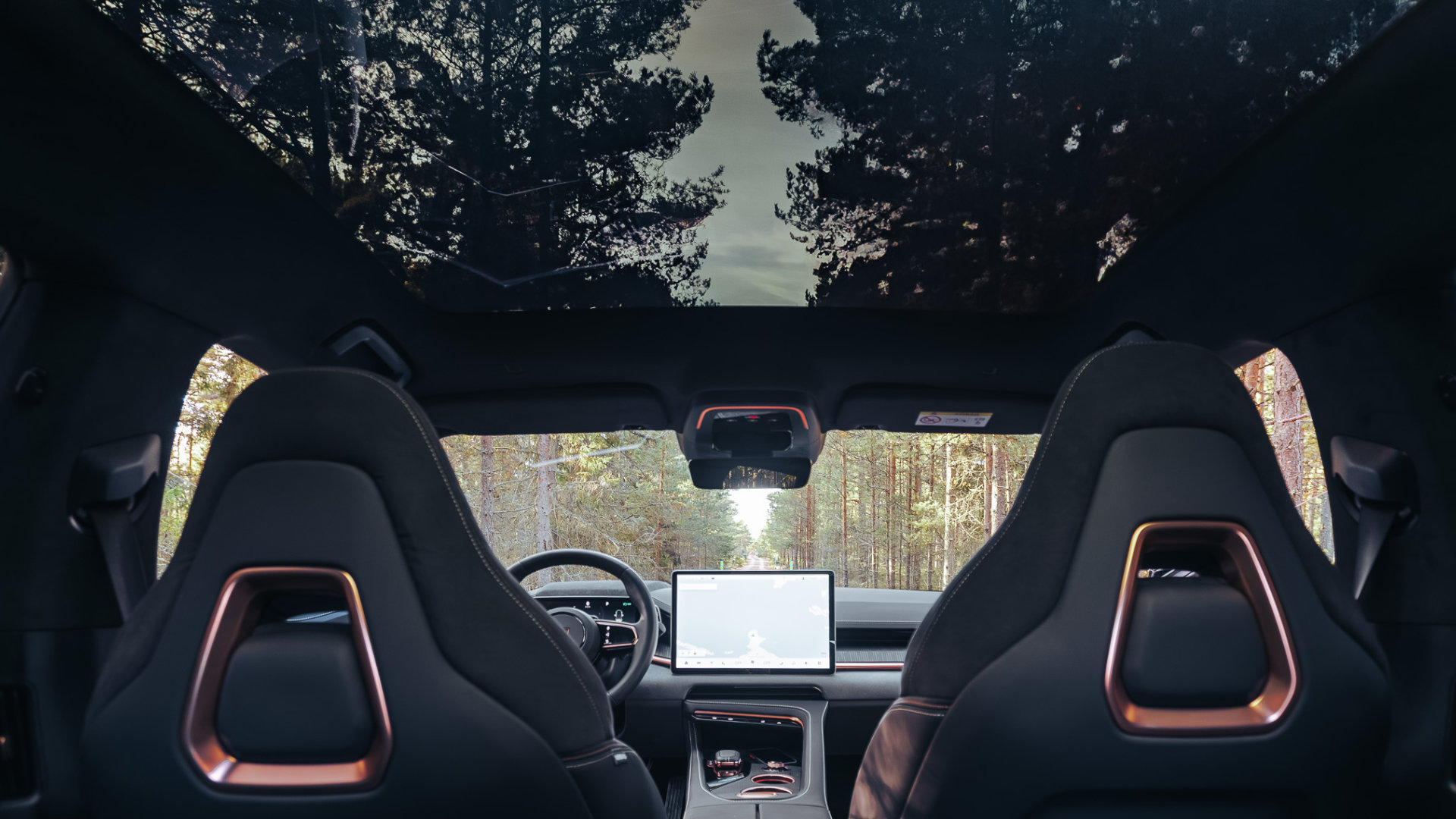 Interiør i Zeekr fra Bilservice – sett fra baksetet med panoramatak, navigasjonsskjerm og utsikt mot skog gjennom frontrute