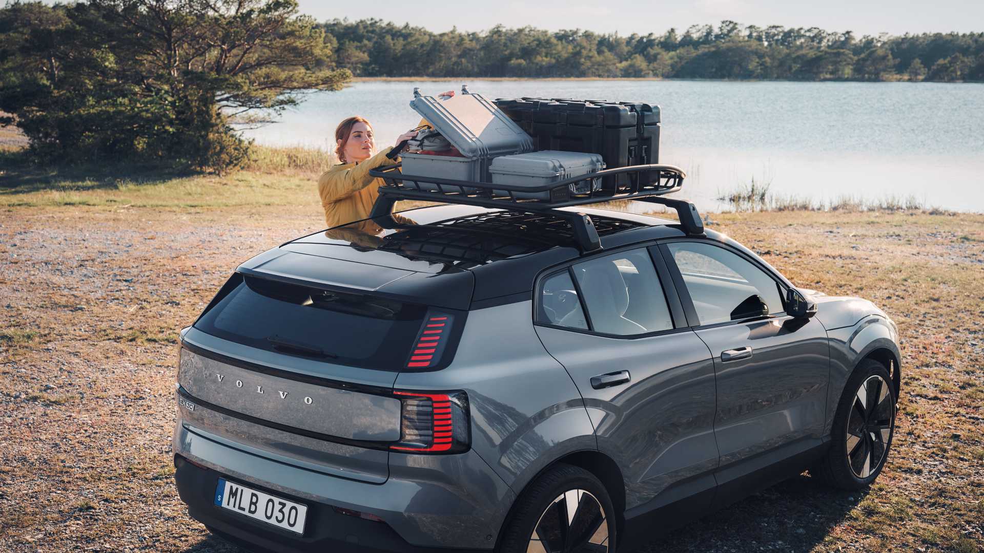fon1 SUV med takboks parkert ved innsjø – person med paddleboard forbereder seg på aktivitet i solnedgang