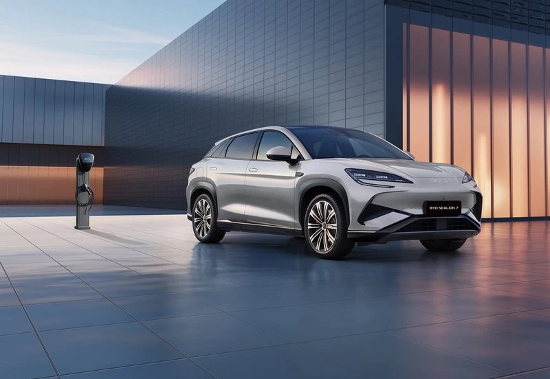 Blå BYD Atto 3 som lades via ladeporten foran venstre skjerm, med detaljerte aluminiumsfelger.