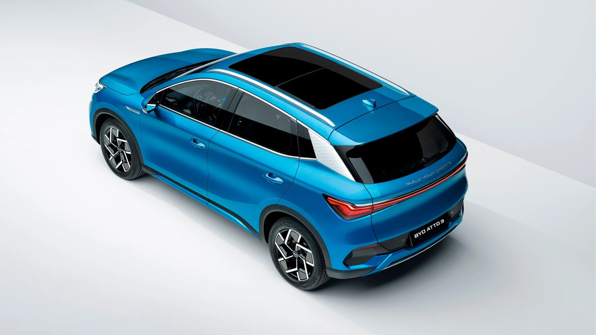 Blå BYD Atto 3 sett bakfra i skrå vinkel ovenfra, med panoramatak og sammenhengende LED‑lyslist bak.