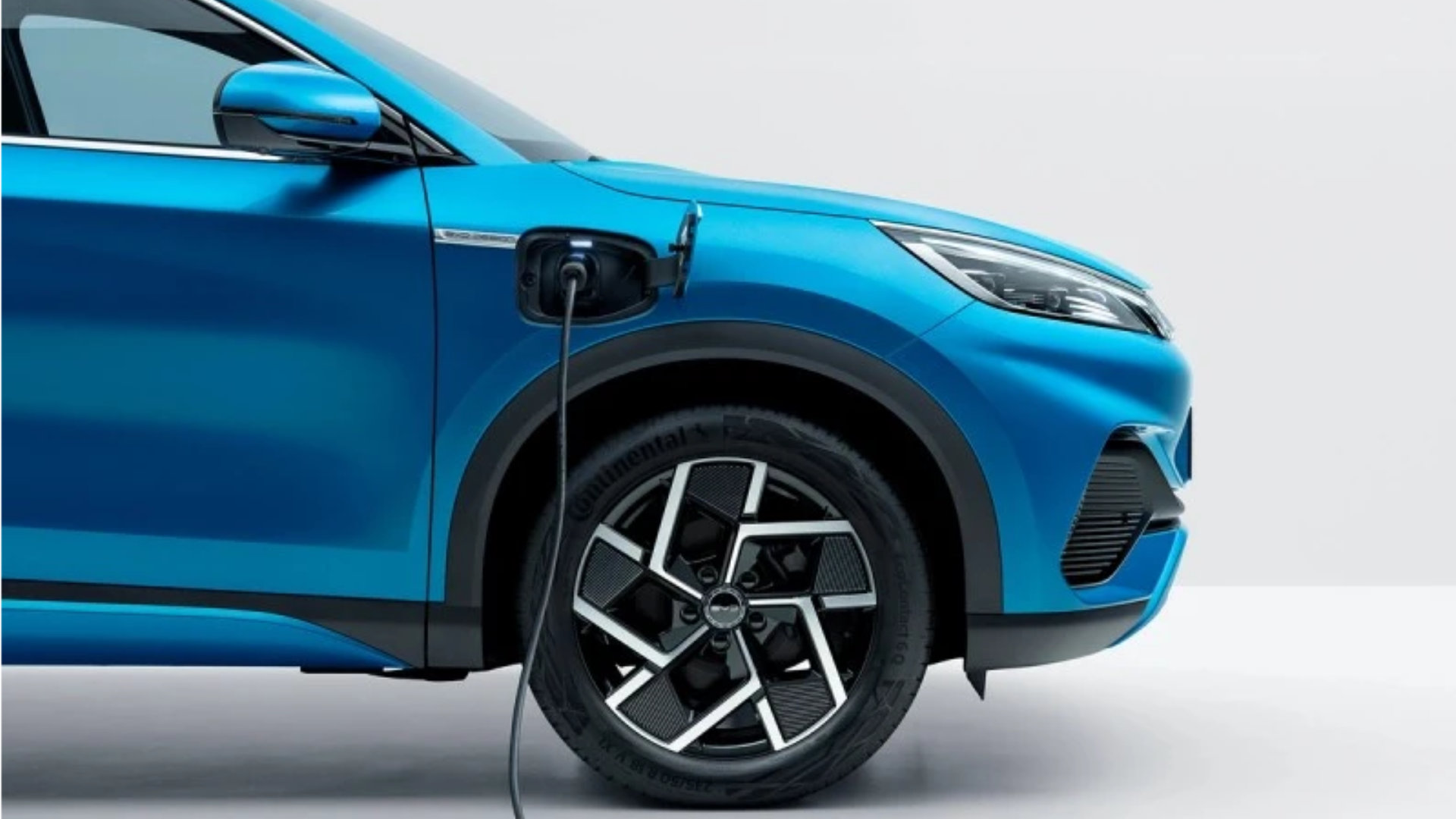 Blå BYD Atto 3 som lades via ladeporten foran venstre skjerm, med detaljerte aluminiumsfelger.