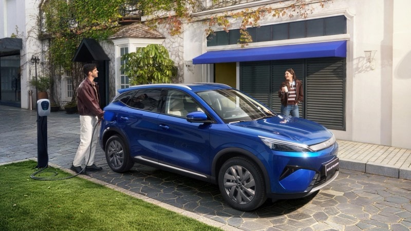 BYD EVO 4x4 i blått parkert ved hjemmelader med to personer i samtale i moderne boligmiljø.
