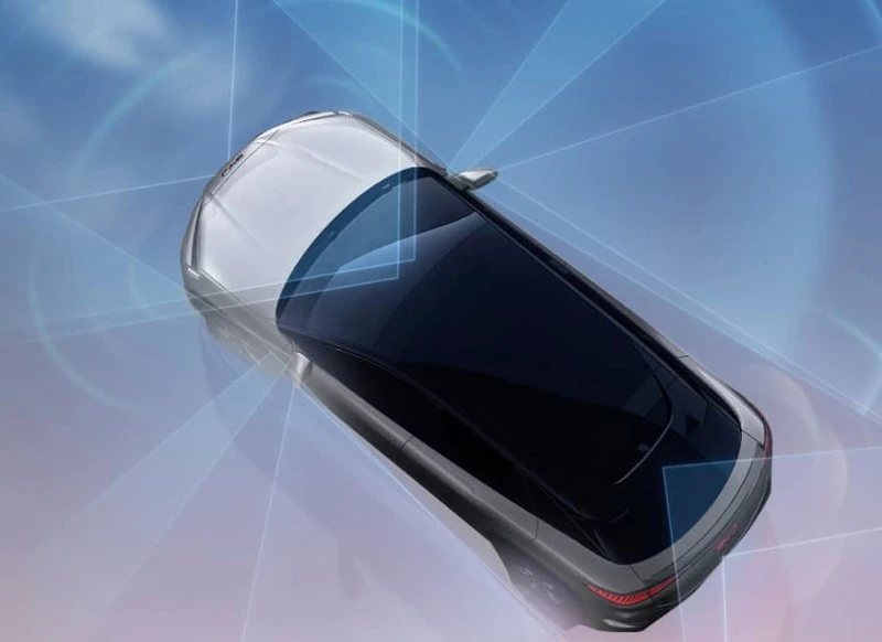 BYD Atto 3 i blå farge parkert ved et telt i fjellandskap om natten, med bilen koblet til lading og et bål ved siden av.